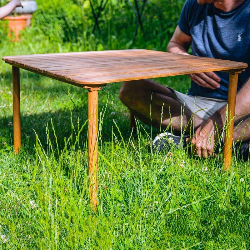 zusammenrollbarer Campingtisch aufgebaut in einem Garten